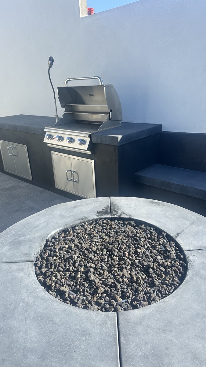 Round concrete fire pit with lava rock and built-in BBQ grill