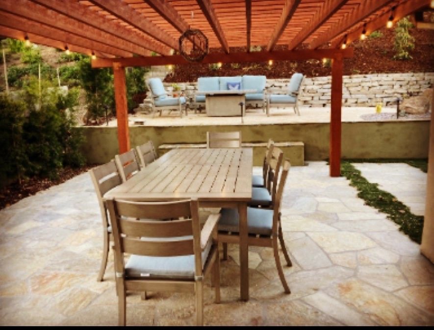 Flagstone patio under a wood pergola with string lights and outdoor dining set