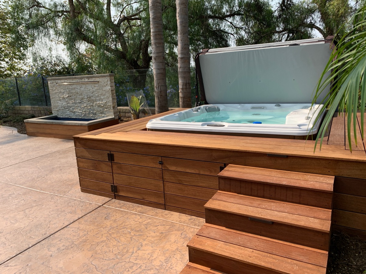 Custom hot tub installation with wood deck surround and steps