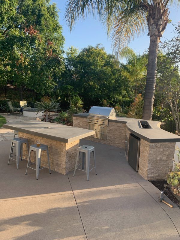 Outdoor kitchen BBQ island with stone veneer, bar counter and stools