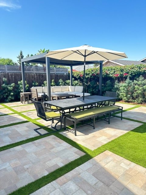 Large paver patio with artificial turf strips, modern pergola and outdoor dining